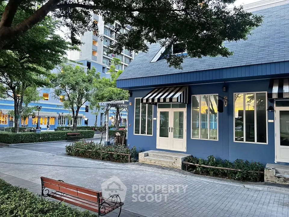 Charming blue building exterior with lush greenery and inviting benches in a serene urban setting.