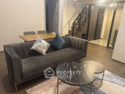 Modern living room with stylish sofa, elegant coffee tables, and dining area in open-plan design.