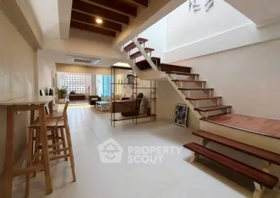 Modern open-plan living area with stylish staircase and natural light