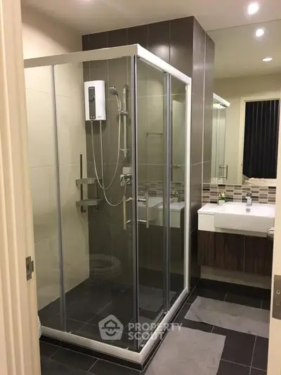 Modern bathroom with glass shower enclosure and sleek vanity in contemporary apartment.