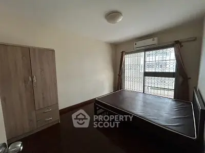 Spacious bedroom with large window and air conditioning in modern apartment.