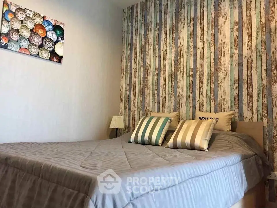 Cozy bedroom with stylish striped wallpaper and comfortable bedding, perfect for relaxation.
