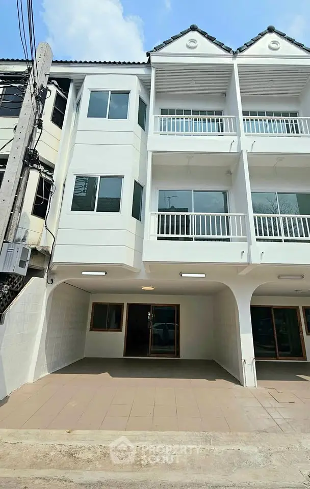 Modern three-story townhouse with balconies and tiled entrance in urban setting.