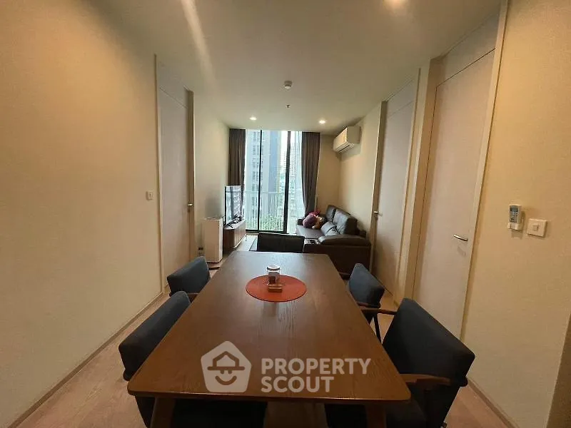Modern living room with dining area and large window view in a stylish apartment.