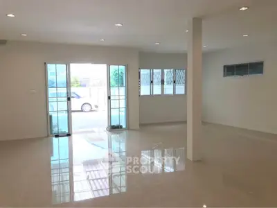 Spacious open-plan living area with large windows and glossy floors