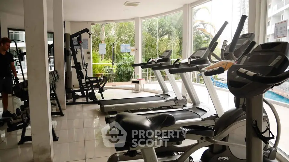 Spacious gym with modern equipment and lush garden view, perfect for fitness enthusiasts.