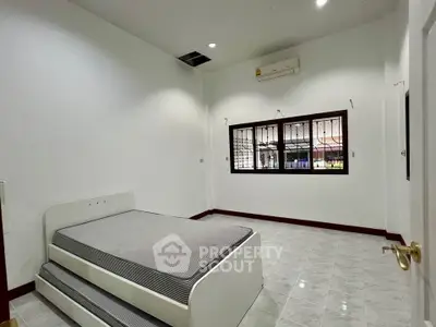 Spacious bedroom with modern design and ample natural light, featuring a sleek bed and air conditioning.