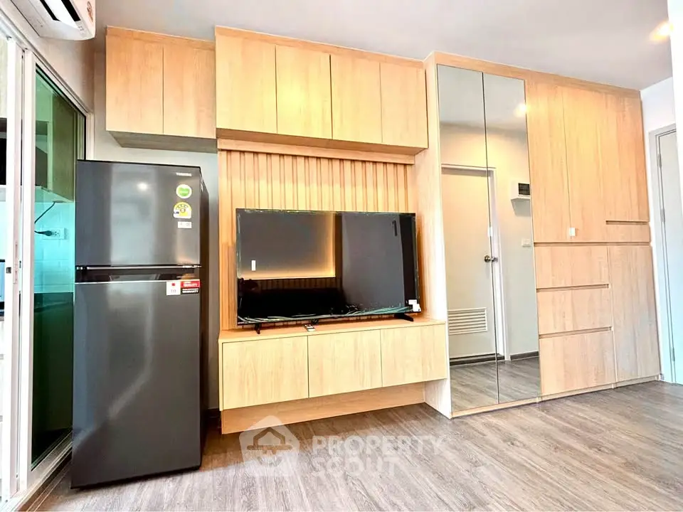 Modern living room with sleek wooden cabinetry and large flat-screen TV