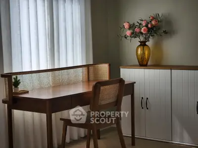 Elegant study room with wooden desk and chair, featuring a decorative vase with flowers.