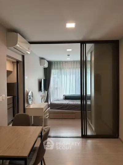 Modern studio apartment with glass partition, cozy bedroom, and stylish dining area.