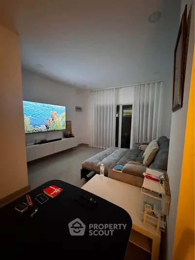 Modern living room with cozy sectional sofa and large TV, perfect for relaxation and entertainment.