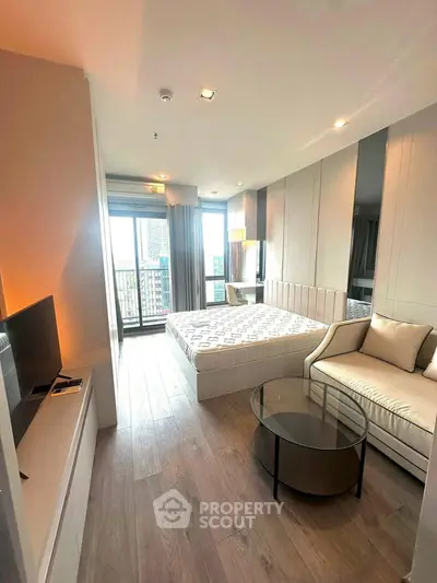 Modern bedroom with balcony view, stylish furniture, and ample natural light.