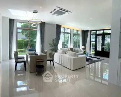 Luxurious open-plan living room with elegant decor and large windows offering garden views.
