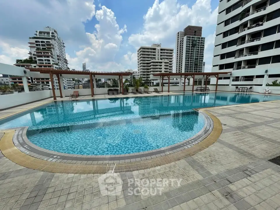 Luxurious rooftop pool with city skyline views in modern apartment complex.