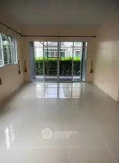 Spacious living room with large windows and garden view, perfect for natural light lovers.