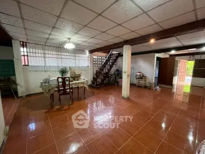 Spacious open-plan living area with tiled flooring and staircase, ideal for customization.