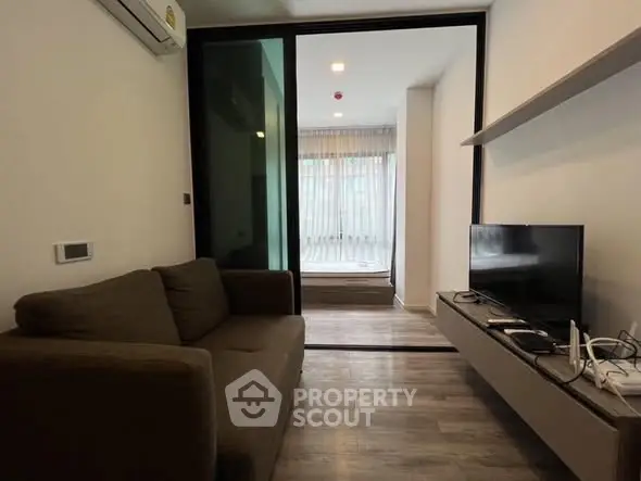 Modern living room with sleek design and cozy sofa, featuring a large TV and stylish shelving.