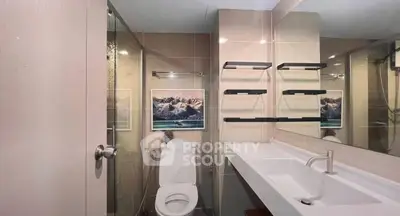 Modern bathroom with sleek fixtures and glass shower enclosure in contemporary apartment.