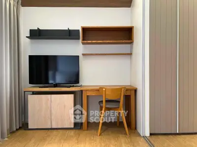 Modern study area with wooden desk, chair, and TV in a stylish apartment.