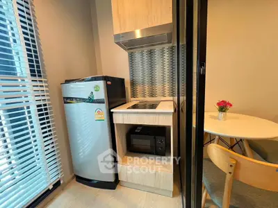 Modern compact kitchen with fridge, stove, and dining area in cozy apartment.