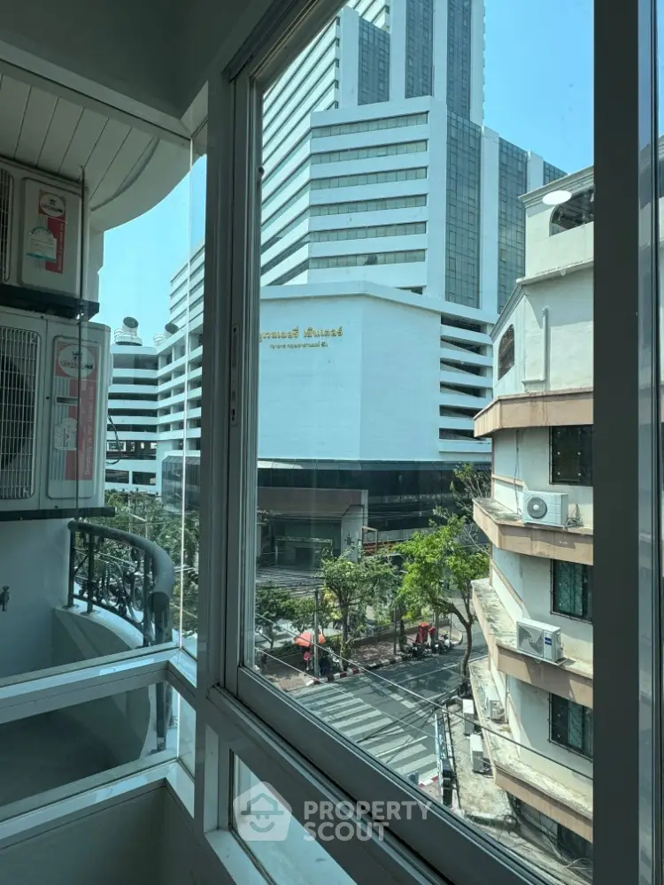 Stunning city view from modern apartment balcony with glass railing and air conditioning unit.