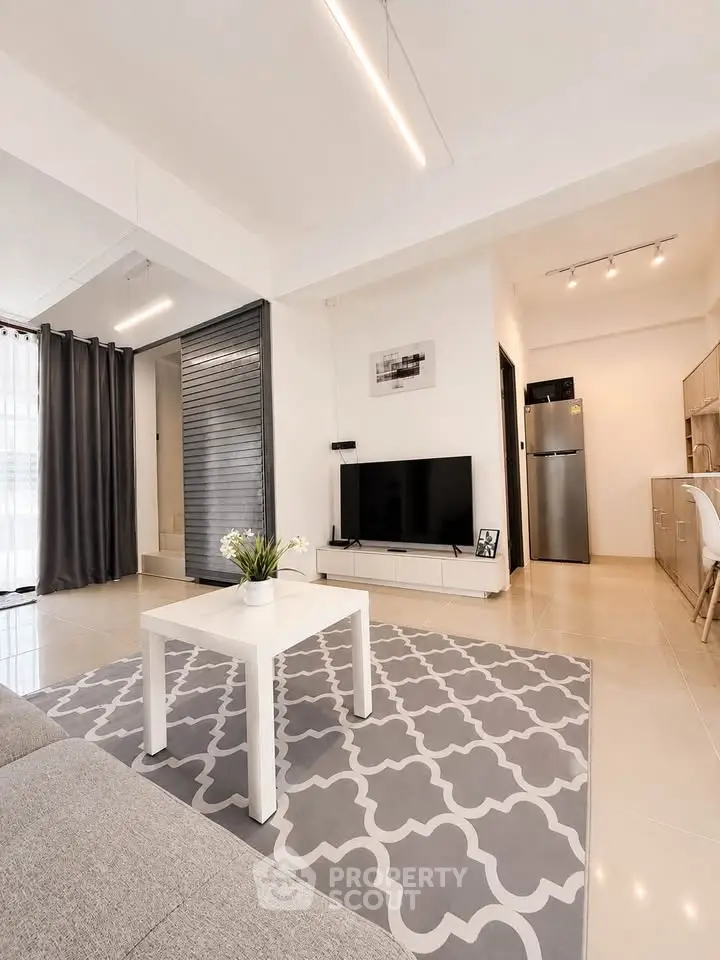 Modern living room with stylish decor, featuring a sleek TV setup and elegant furniture.
