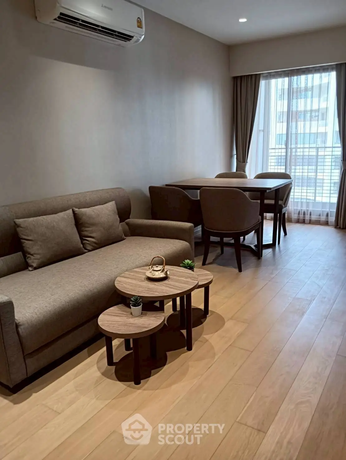 Modern living room with cozy sofa and dining area, featuring large window for natural light.