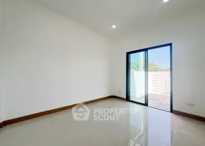 Spacious empty room with sliding glass door leading to a sunny balcony, perfect for customization.