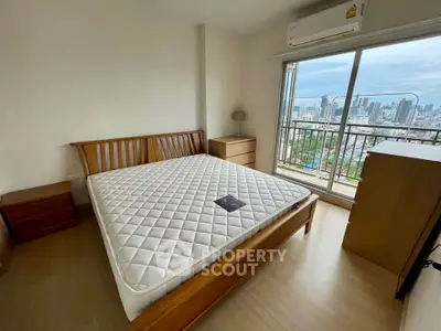 Spacious bedroom with city view and large balcony access in modern apartment.