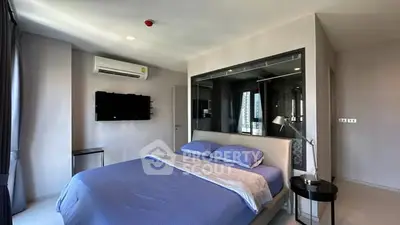 Modern bedroom with blue bedding and wall-mounted TV in a stylish apartment.