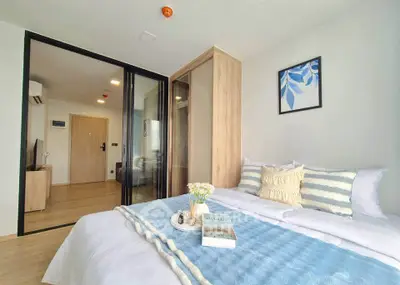 Modern bedroom with stylish decor and glass partition, featuring cozy bedding and natural light.