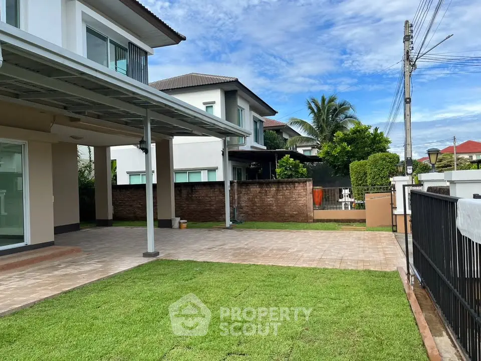 Spacious suburban home with lush green lawn and paved patio area.