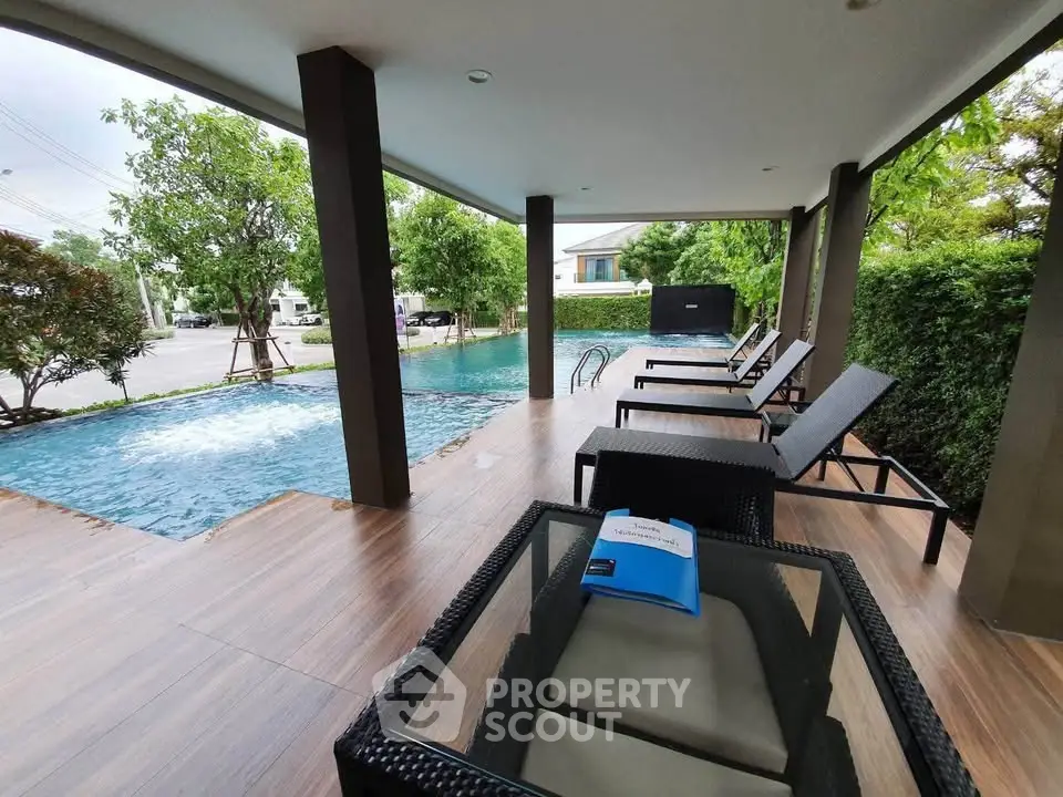 Luxurious outdoor pool area with stylish lounge chairs and lush greenery, perfect for relaxation and leisure.
