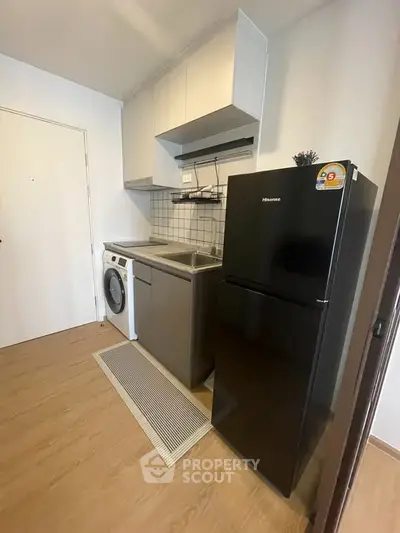 Compact kitchen with modern appliances and washing machine in cozy apartment