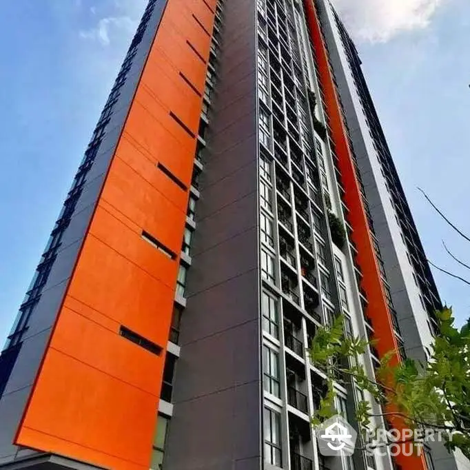 Modern high-rise building with vibrant orange accents and sleek design.