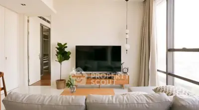 Modern living room with large TV, stylish furniture, and floor-to-ceiling windows offering natural light.