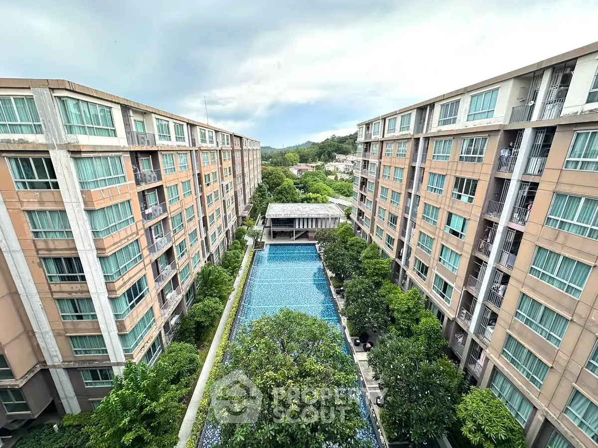 Stunning aerial view of modern apartment complex with central pool and lush greenery.