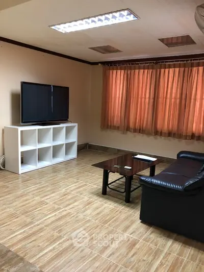Cozy living room with leather sofa and TV, perfect for relaxation.