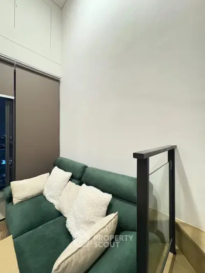 Modern living room with green sofa and glass railing in a stylish apartment