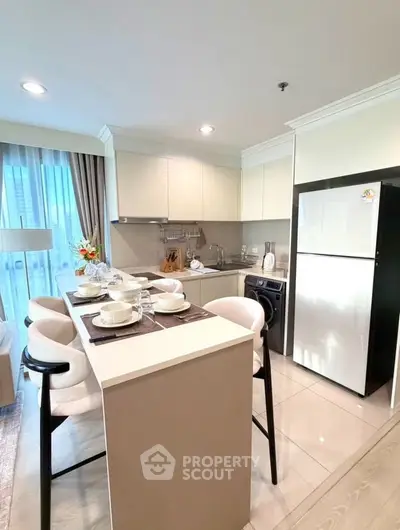 Modern kitchen with sleek design, featuring a breakfast bar and stainless steel appliances.