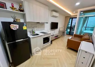 Modern living room with open kitchen, featuring sleek appliances and cozy seating area.