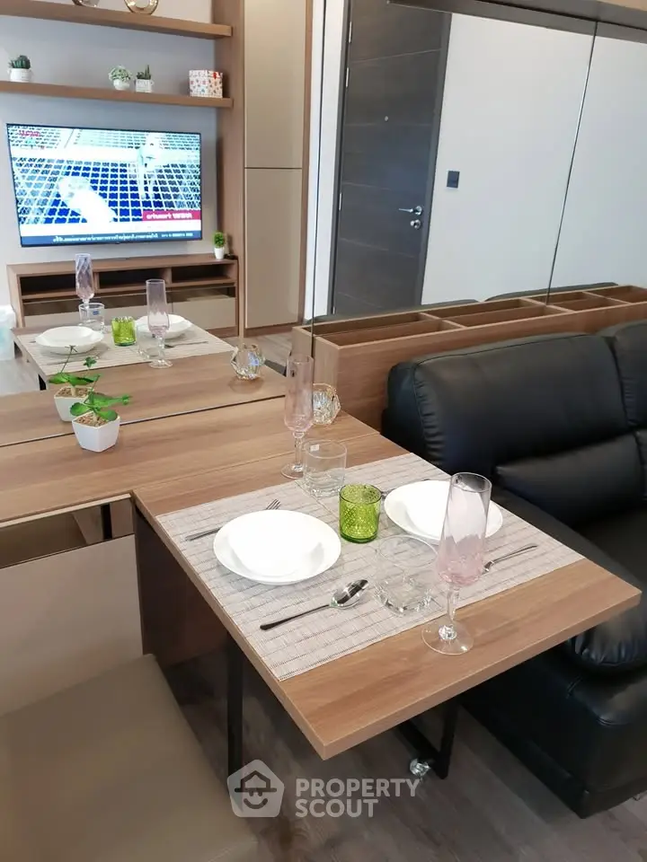 Modern living room with stylish dining setup and TV, featuring sleek furniture and elegant decor.