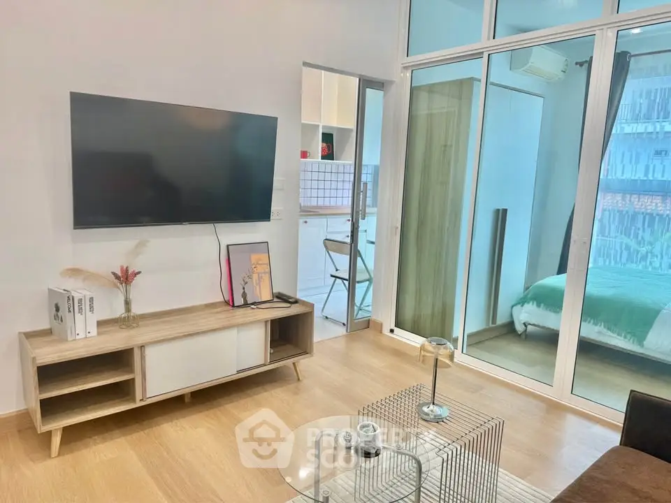 Modern living room with TV, stylish furniture, and glass doors leading to a cozy bedroom.