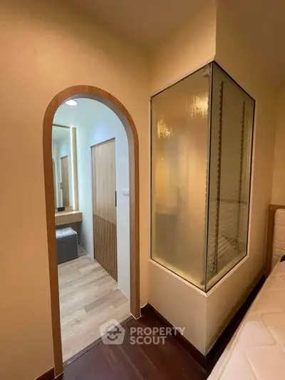Modern bedroom with unique frosted glass feature and stylish wooden archway entrance.