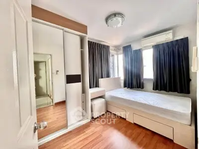 Cozy bedroom with wooden flooring, mirrored wardrobe, and ample natural light.