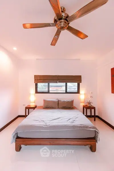 Spacious bedroom with elegant wooden bed and ceiling fan, perfect for relaxation.