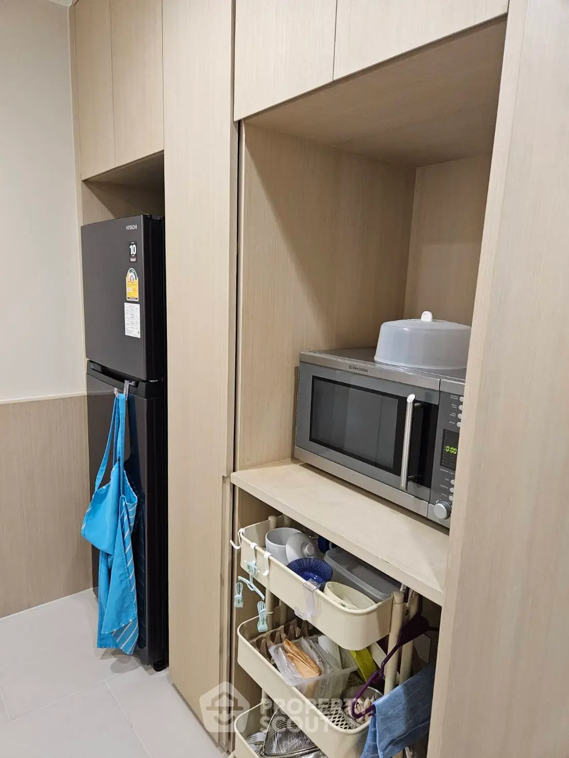 Modern kitchen with sleek cabinetry, microwave, and organized storage solutions.