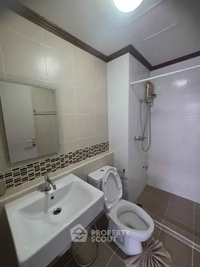 Modern bathroom with sleek fixtures and tiled walls, featuring a shower and toilet.