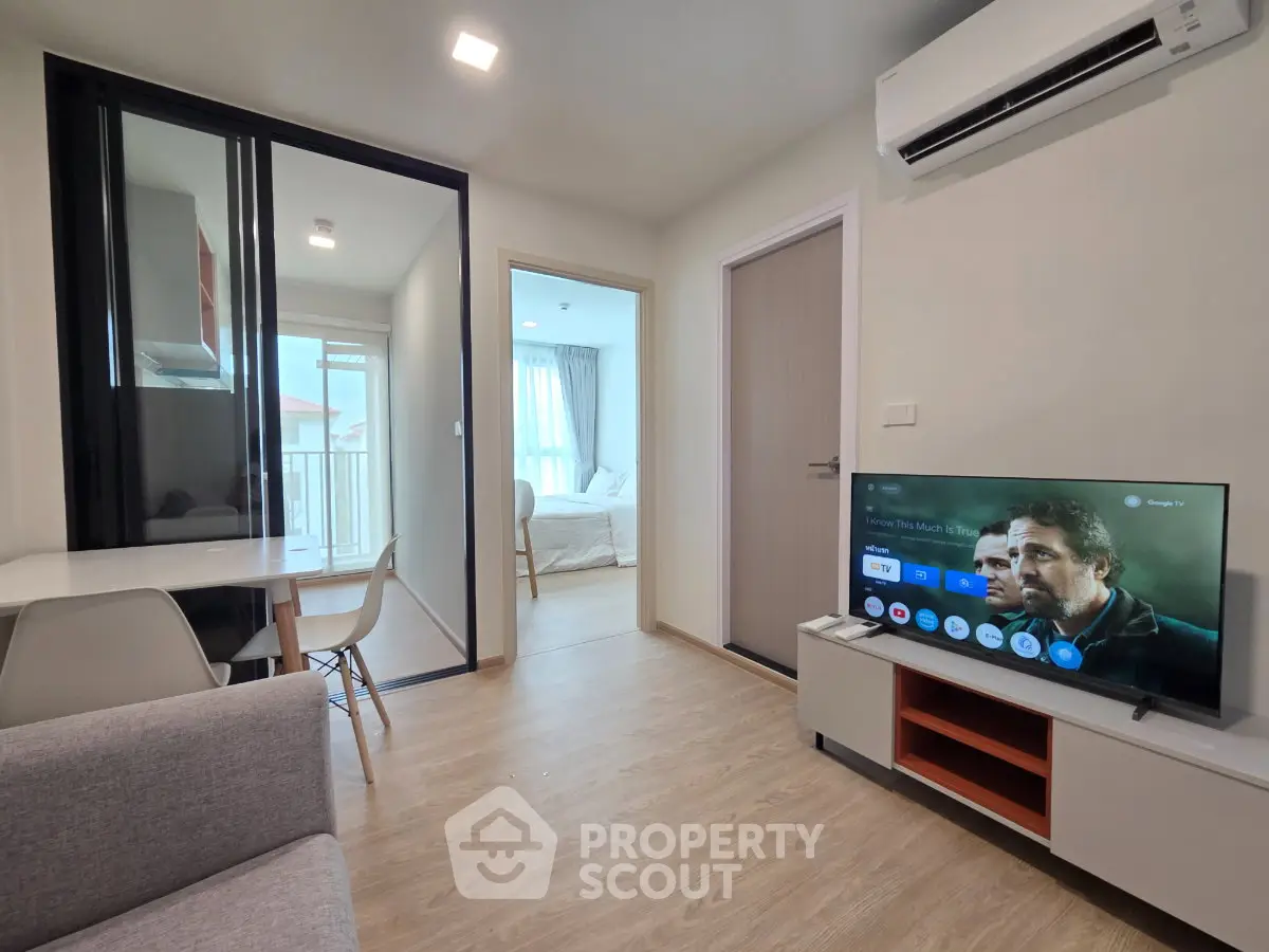 Modern living room with TV, air conditioning, and view into bedroom in stylish apartment.
