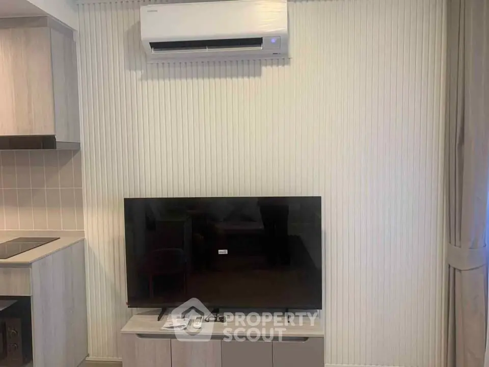 Modern living room with air conditioning and flat-screen TV, featuring sleek cabinetry and neutral tones.